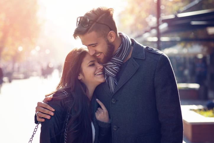 Young smiling couple, cuddling and walking on the street