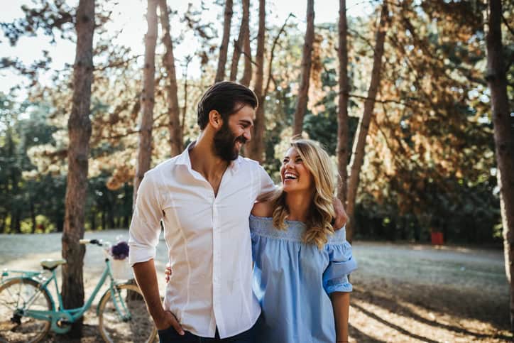 Happy couple cuddling while walking in the woods.