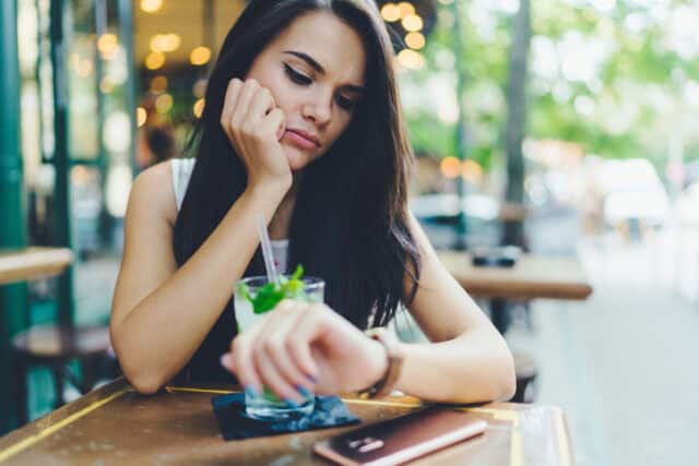 woman looking at watch time at cafe