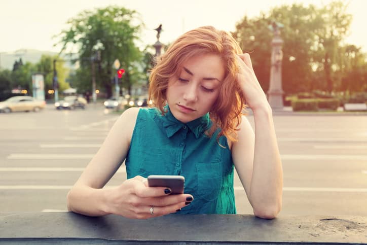 Teenage girl breaking up with her boyfriend while sitting on a bridge near big boulevard. Casual clothing with shirt and jeans.