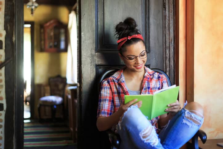 Smiling young woman with headband reading a book