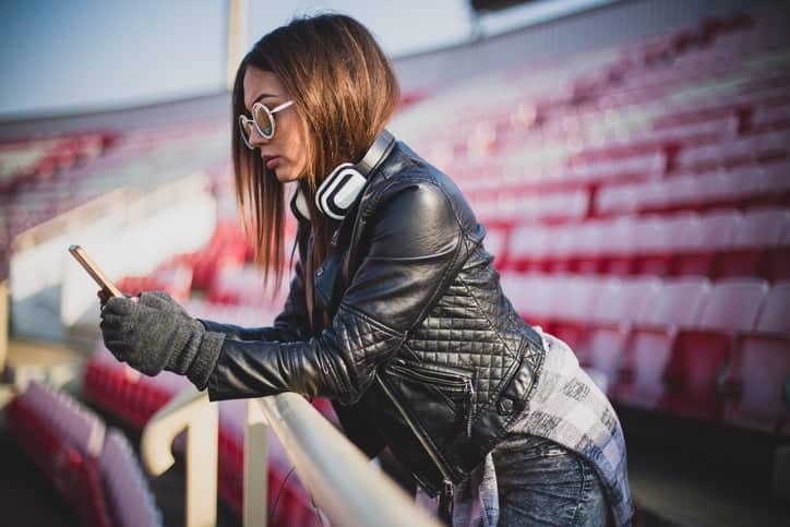Beautiful girl with a headphones and smart phone on the tribune