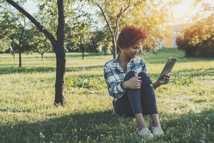 Mixed girl with digital tablet in park