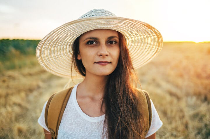 Girl with straw hat in the meadow field.