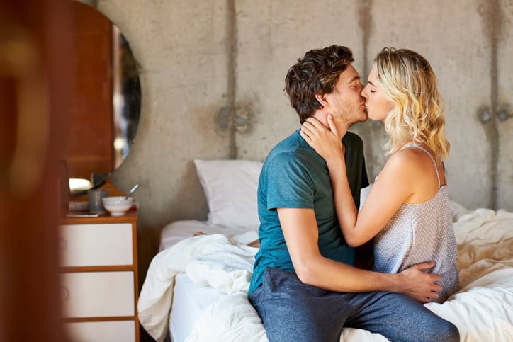 Romantic young couple kissing on bed