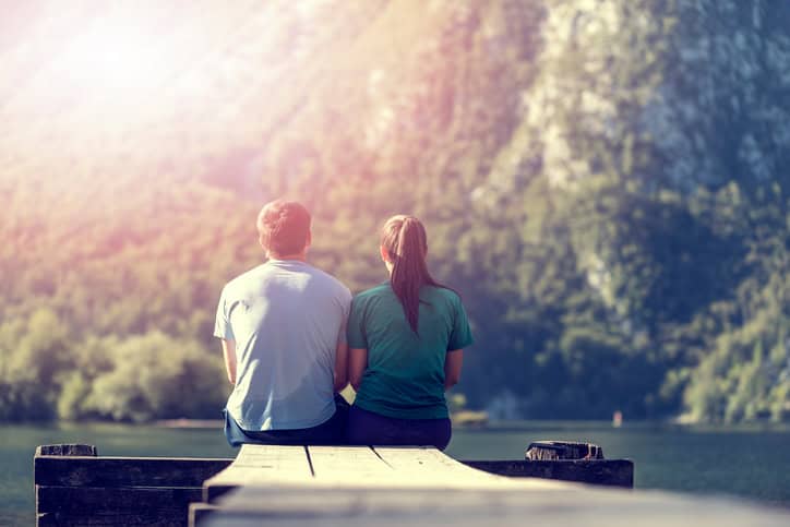 couple sitting on the edge of a dock