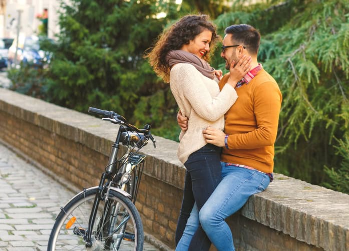 Happy young couple with a bicycle on sunny autumn day in the city.