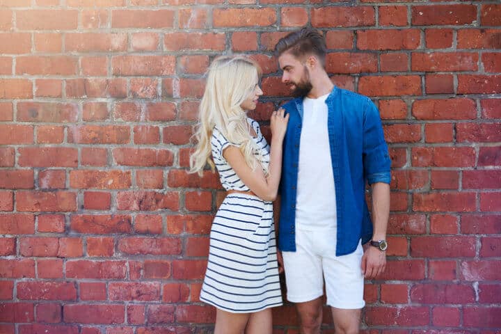 Loving couple standing brick wall