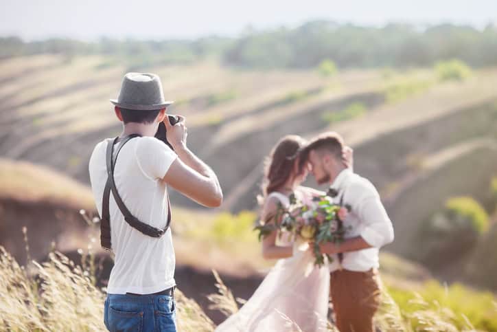 Wedding photographer takes pictures of a bride and groom.
