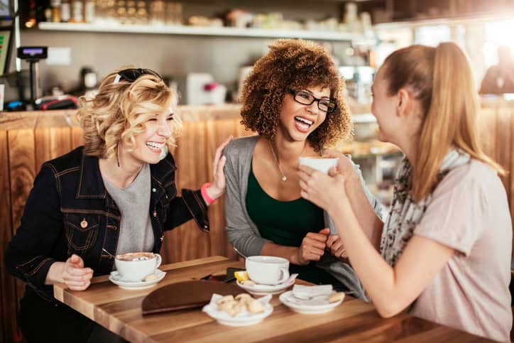 Close up of best friends using a mobile phone while at a cafe