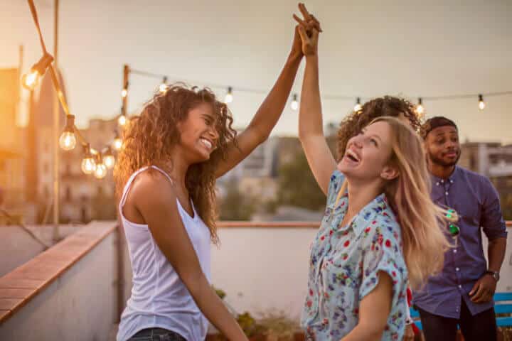 Female friends dancing during party on terrace
