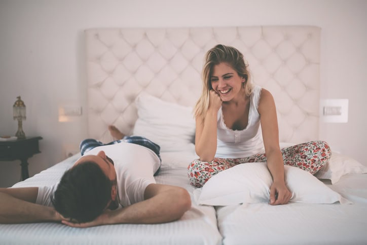 Happy couple in pajamas having conversation in bed