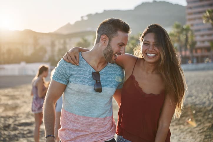 Portrait of young happy couple embracing each other on beach laughing