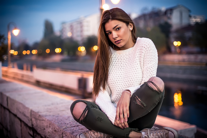 dark haired woman crouching in the street