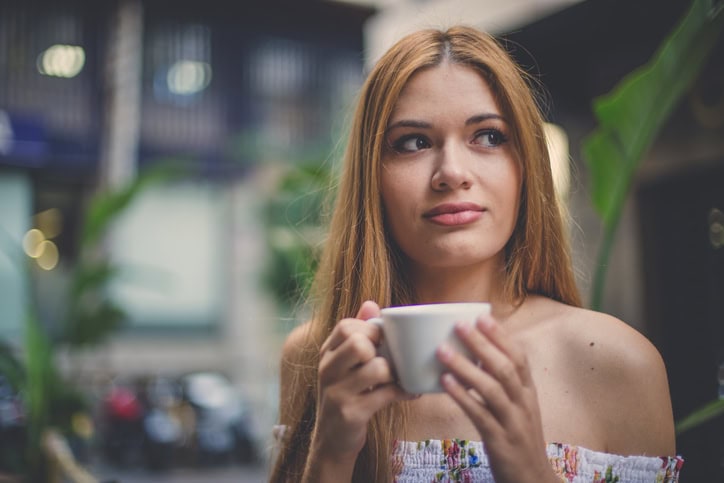 Young woman sitting in cafe and drinking coffee