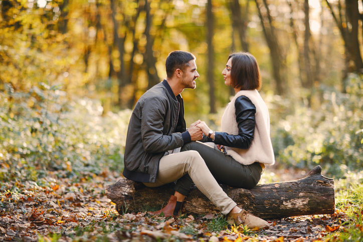lovely couple sitting in the park during autumn