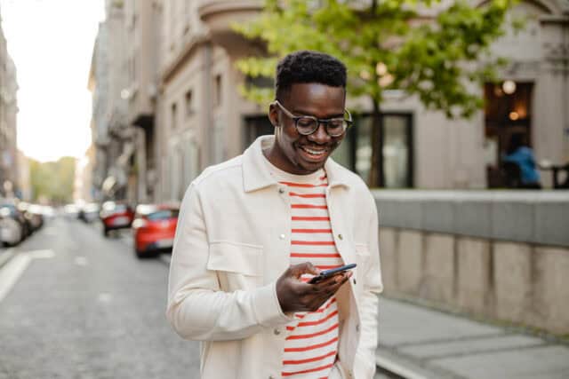 smiling guy texting on city street