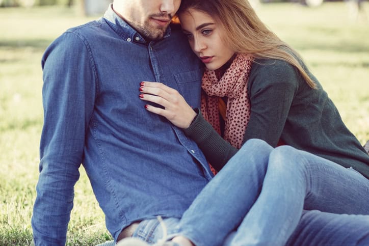 couple hugging sat on the grass