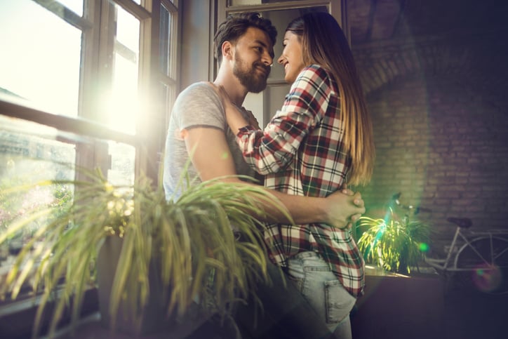 Young couple enjoying in their love by the window at their new apartment.