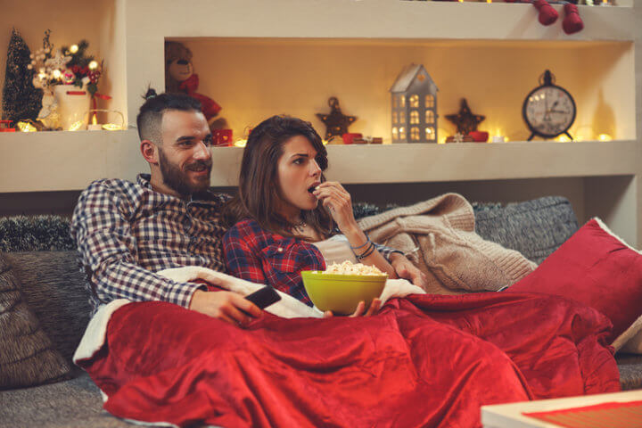 Couple at home eating pop corns while watching movie on tv