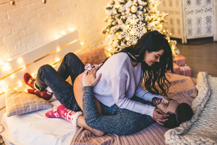 assionate romantic couple spending time before New Year near beautiful Christmas tree at home