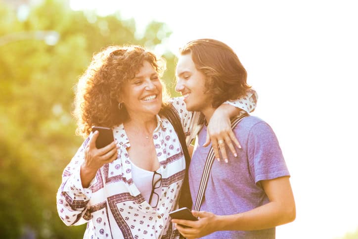 Happy mature mother and son share victory on mobile game