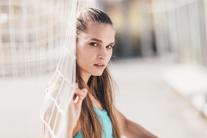 woman leaning against a soccer goal net