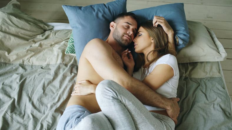 Young beautiful and sexy couple kissing on bed in the morning