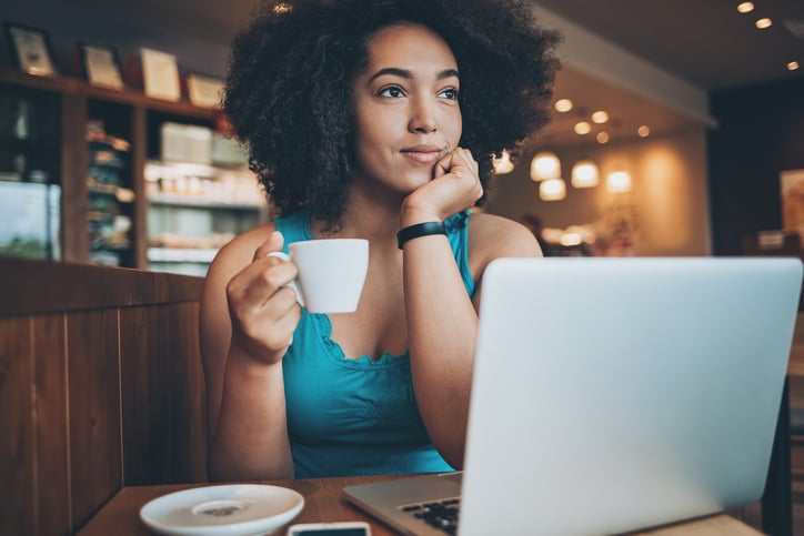 Young woman with laptop drinking coffee in a restaurant