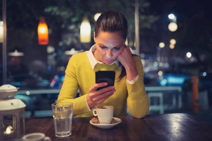 Young woman in a cafe using mobile phone. Shallow DOF