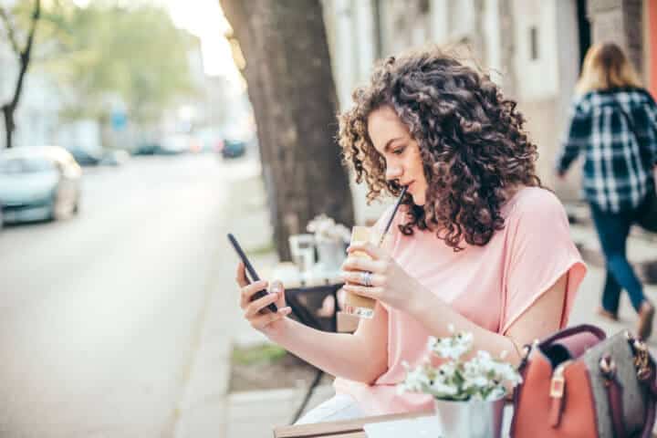 Texting and drinking coffee in a cafe