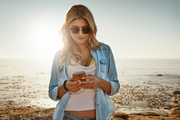 blonde woman texting on beach