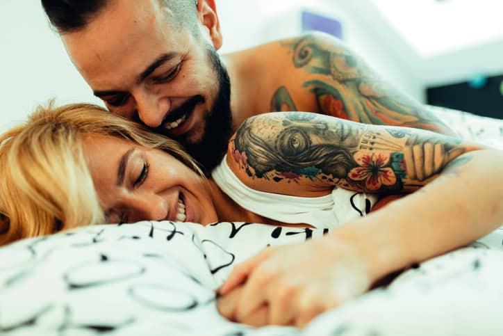 couple with tattoos in bed