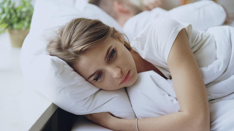 woman sad laying in bed