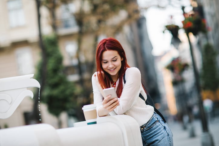 red haired woman smiling and texting