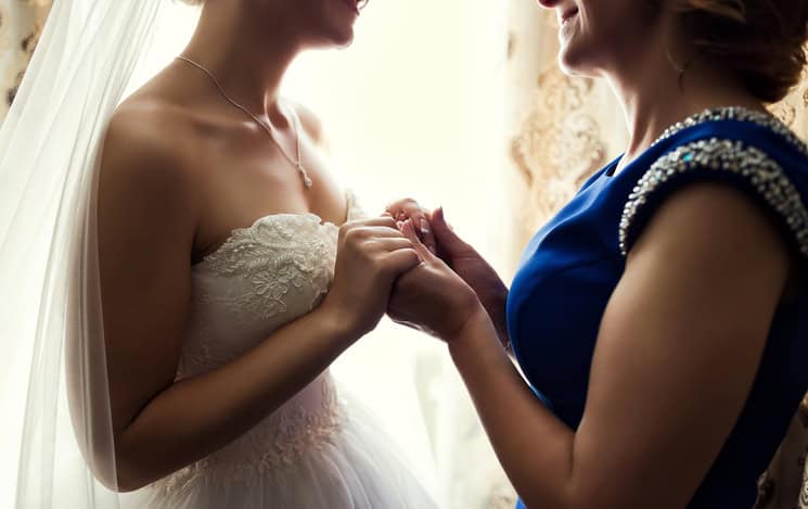 Bride on wedding day holding her mother's hands. Concept of relationship between moms and daughters
