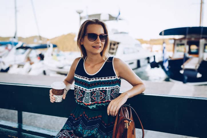 Smiling woman enjoying coffee to go during her summer vacation