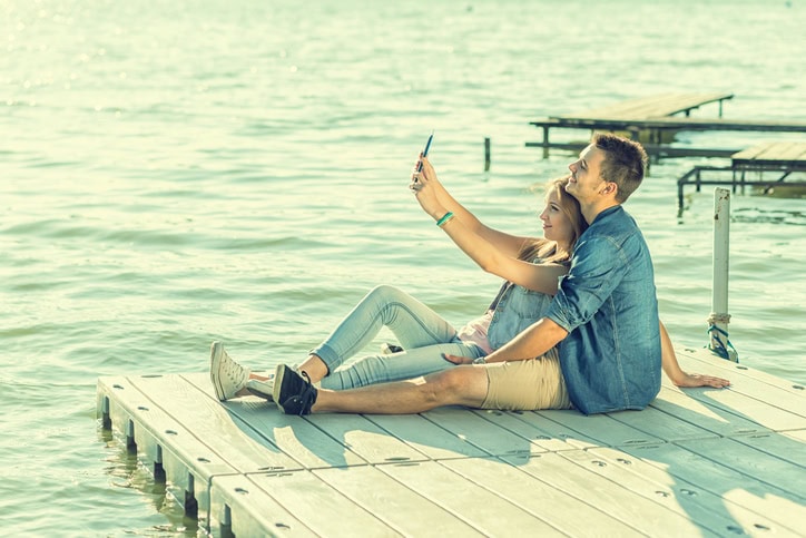 Couple in love sitting on the pier, selfie