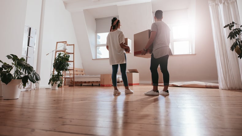 Couple moving boxes together.