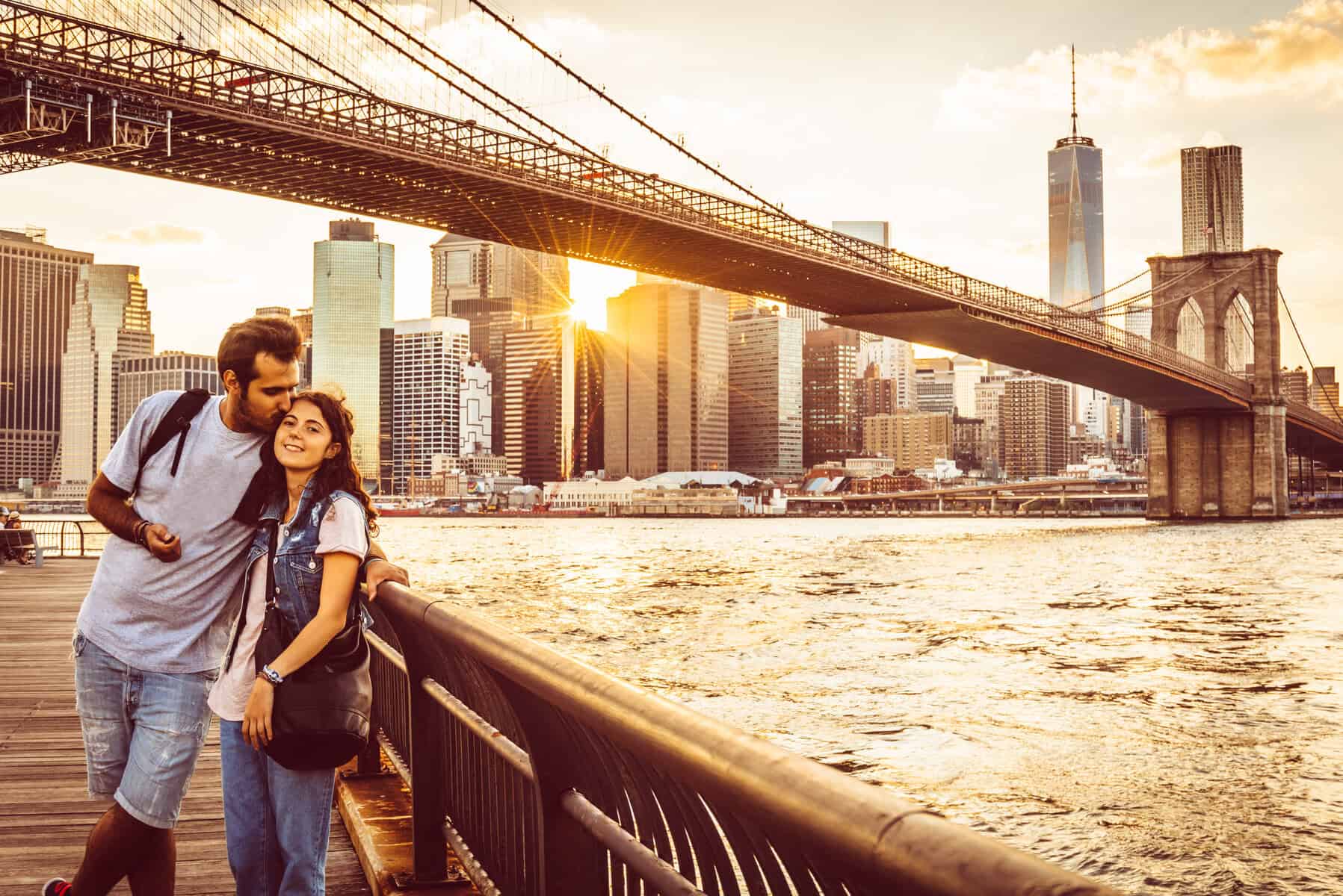Young Couple Under Brooklyn Bridge at sunset.