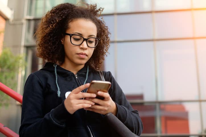 Young millenial girl texting on her mobile phone