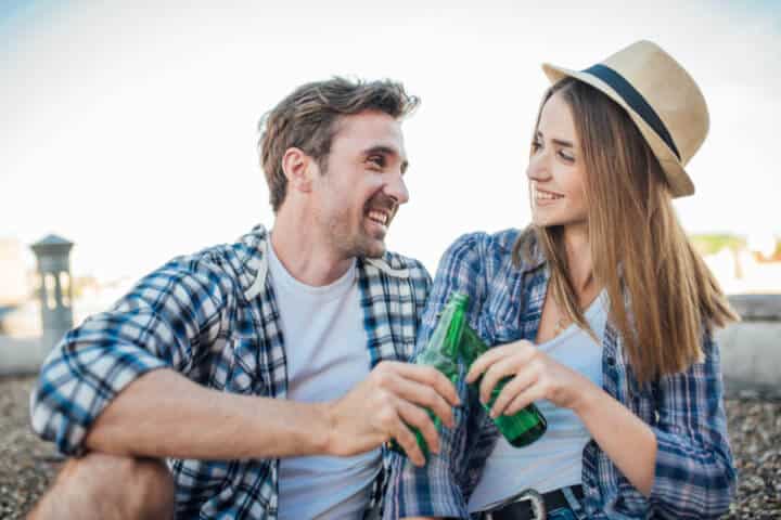Happy couple holding beer bottles on building roof