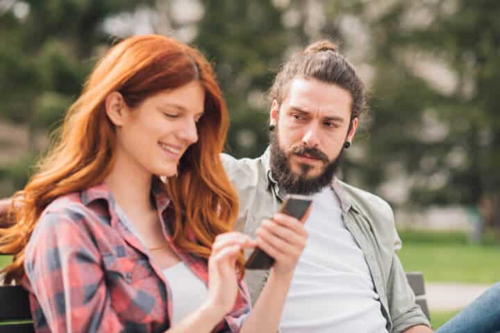 woman texting man looking jealous