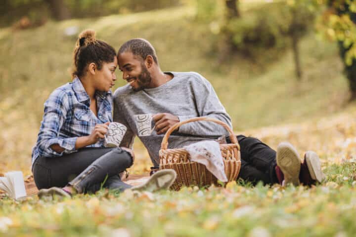Happy black couple enjoying in their love on a picnic at the park.