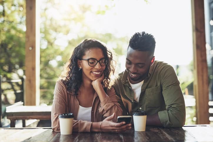 Shot of a woman using her cellphone while sitting in a cafe with her boyfriend