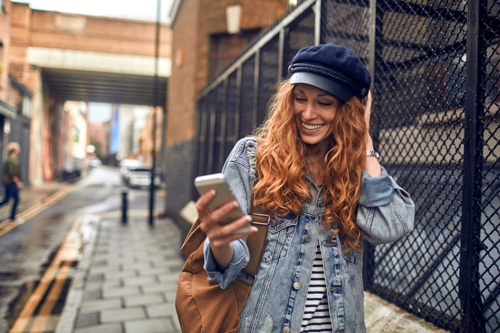 Woman smiling and looking at her phone.