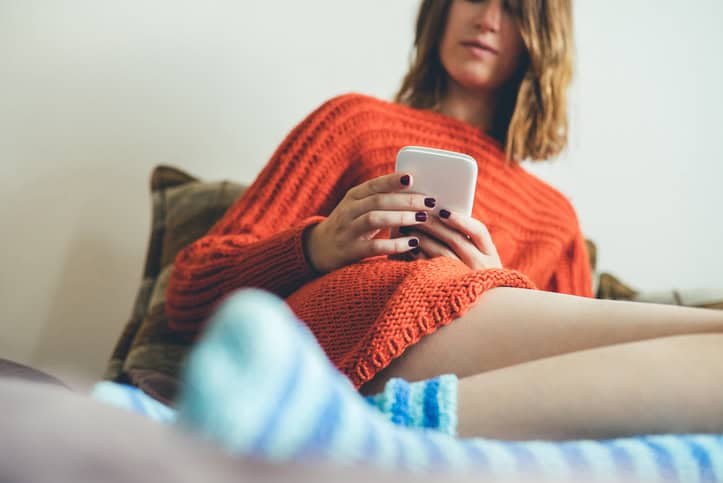 Young woman with colorful socks sitting on bed.