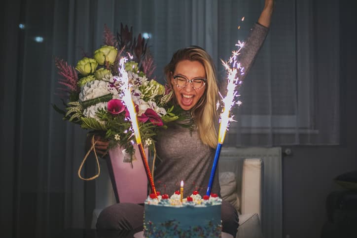 Caucasian woman with flowers and her birthday cake