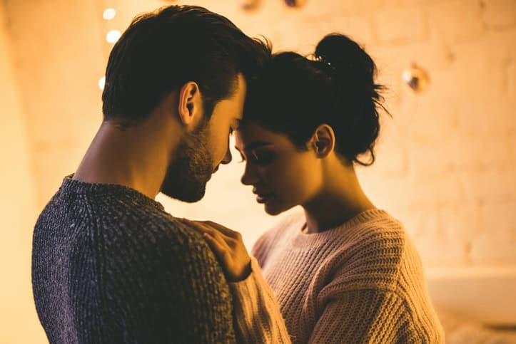 Passionate romantic couple in sweaters are spending time together before New Year at home.