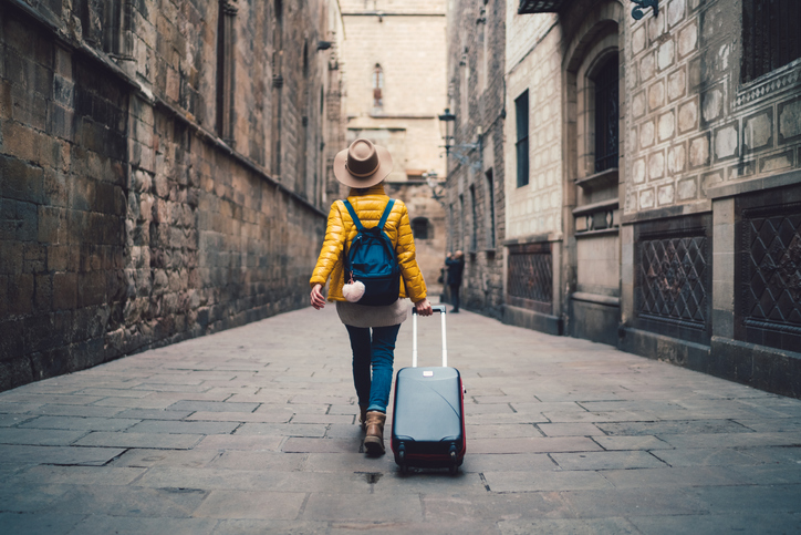 Young woman with suitcase walking on the street in Barcelona.